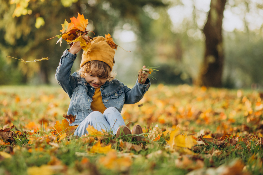 Niño jugando con hojas de otoño